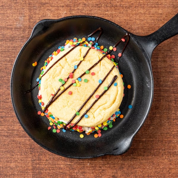 A Grampie's Pizzeria dessert: a large cookie sandwich with sprinkles and chocolate drizzle in a skillet.