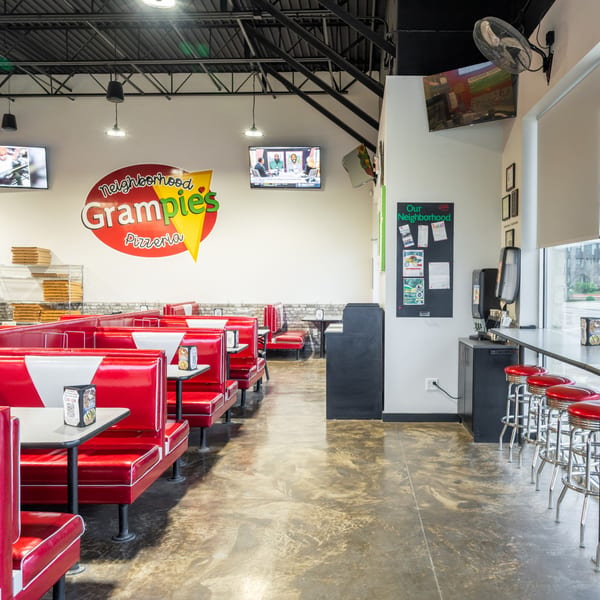 Interior of Grampie's Pizzeria with red booths, bar stools, and a large logo on the wall.