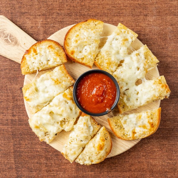 Cheesy garlic bread slices with melted mozzarella and herbs, arranged around a bowl of marinara sauce.